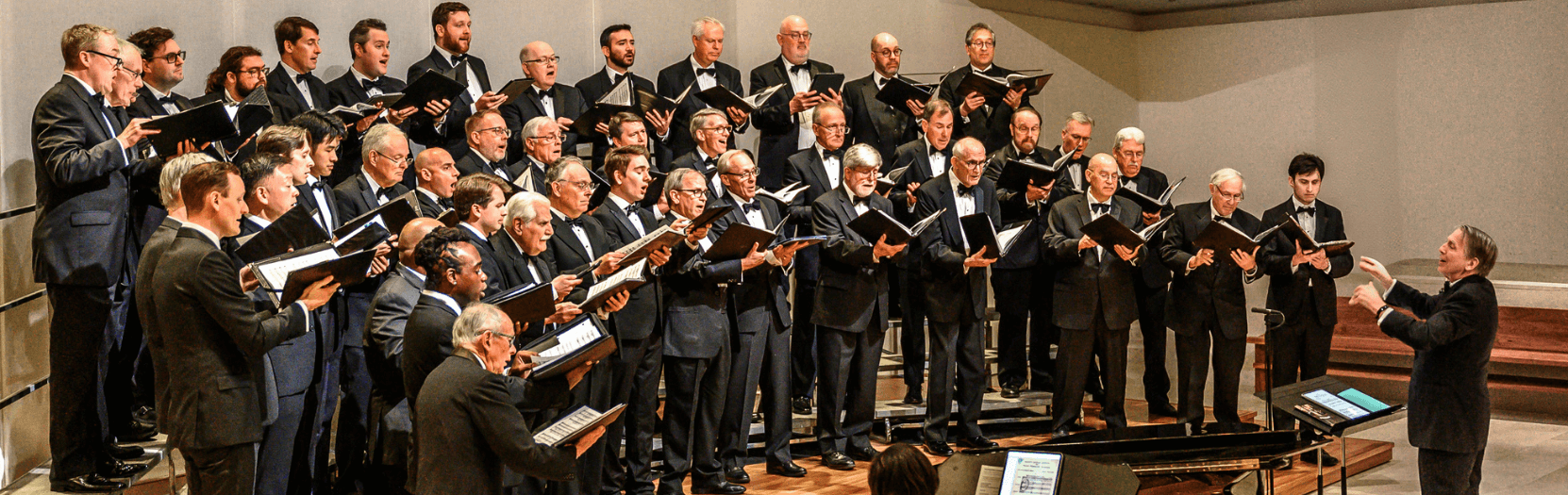 A group of men on a stage, singing.