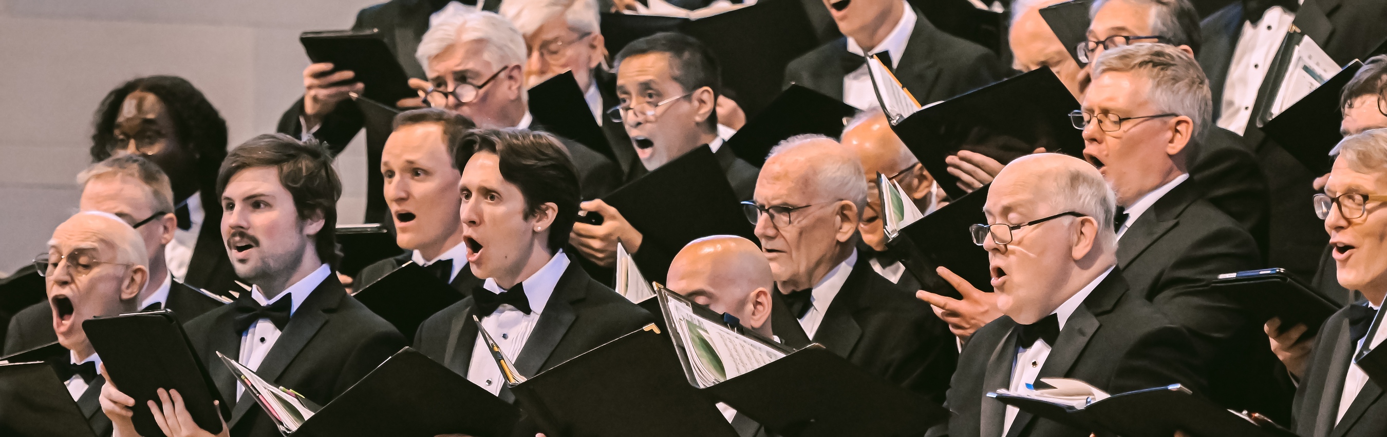 Washington Men’s Camerata singers performing together with open music folders.